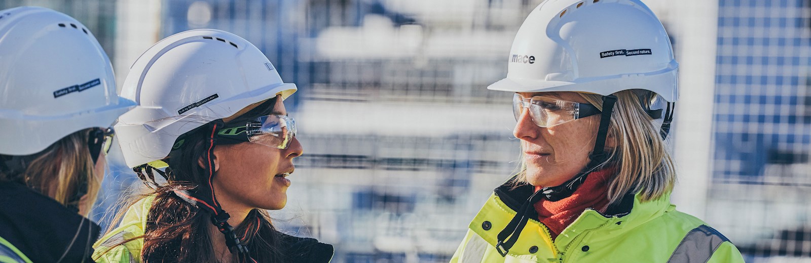 Two women in hivis jackets on a construction site in the daytime 
