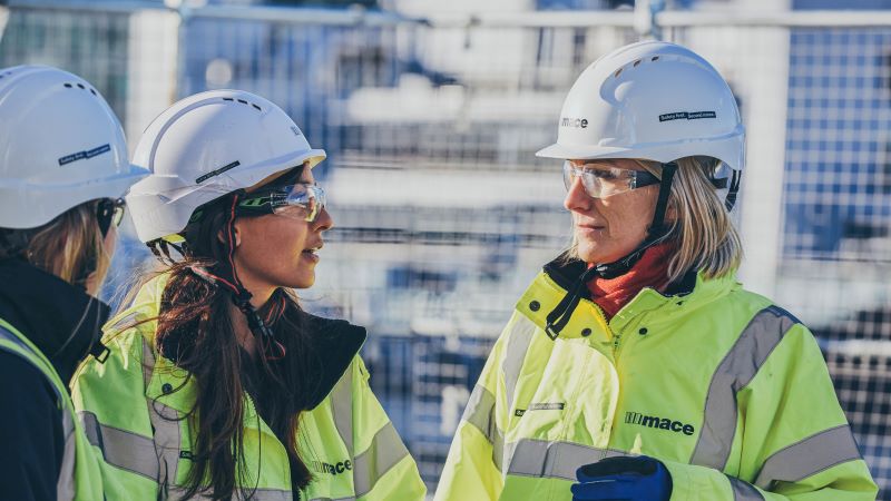 Two women in hivis jackets on a construction site in the daytime 