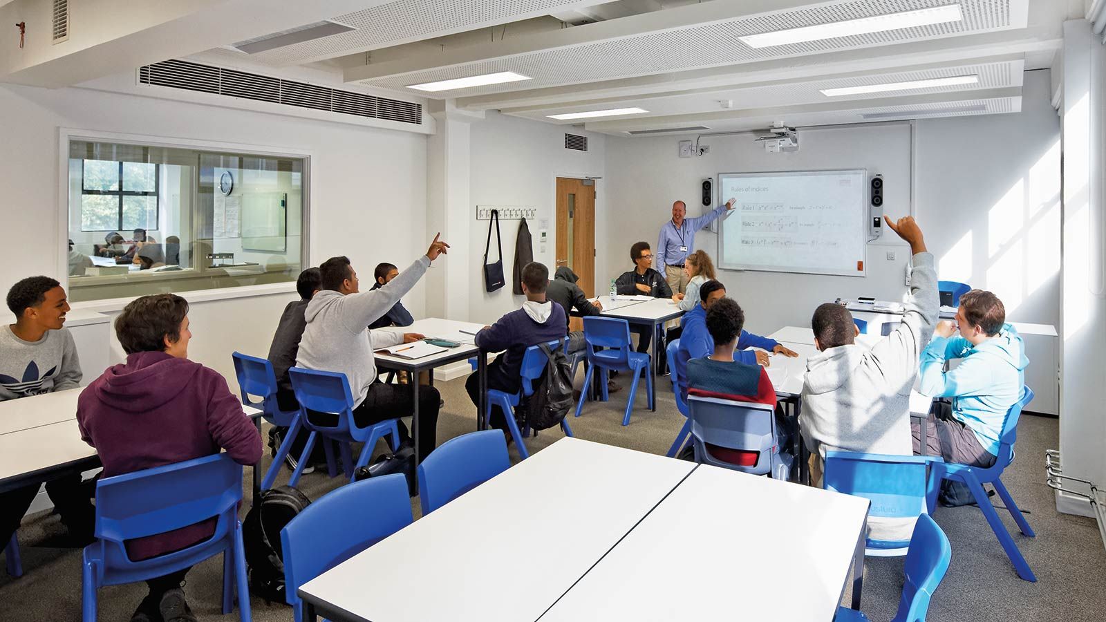 Pupils raising their hand in a class room - Mace Group
